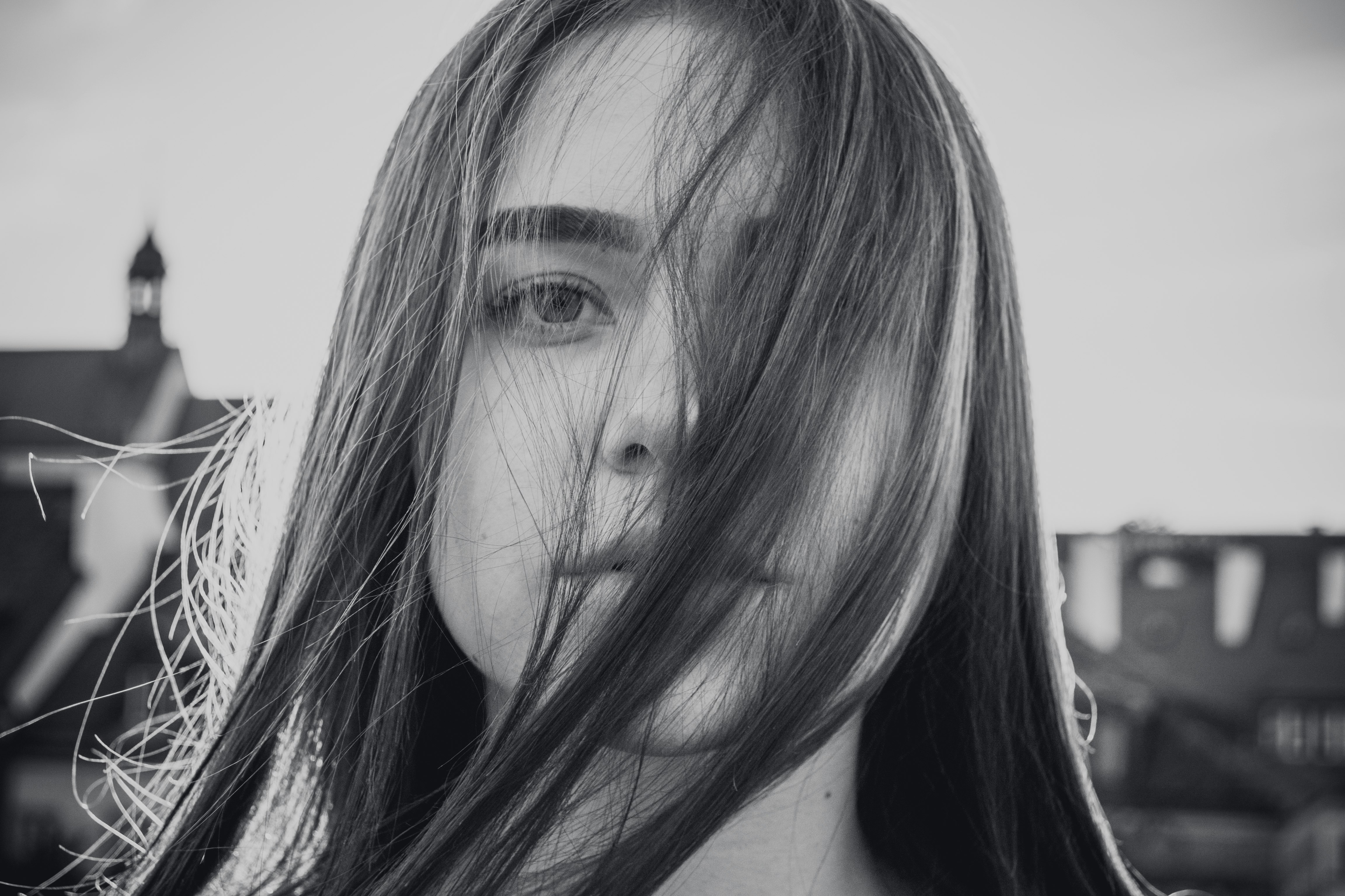 grayscale photo of woman covering her face on her own hair